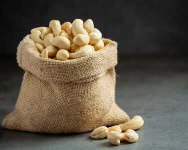 Raw cashews nuts in bag on dark background